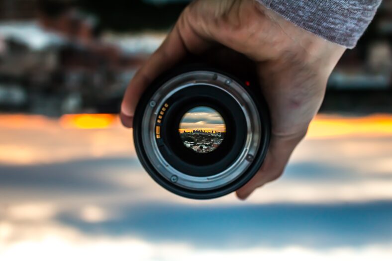 strains for focus header: camera lens in front of sunset.