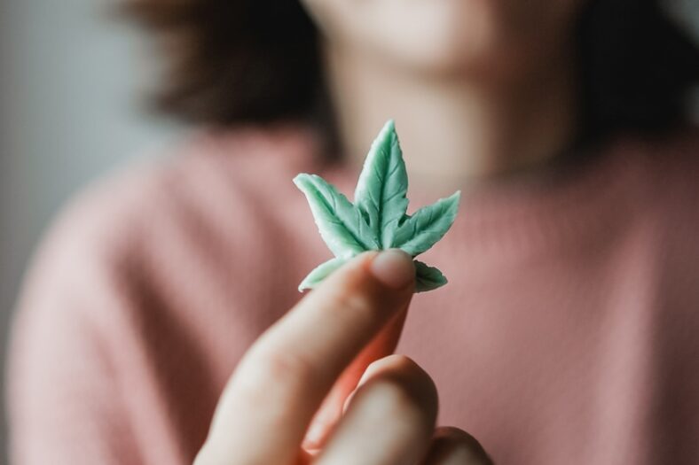 woman holding up a small green cannabis chocolate edible